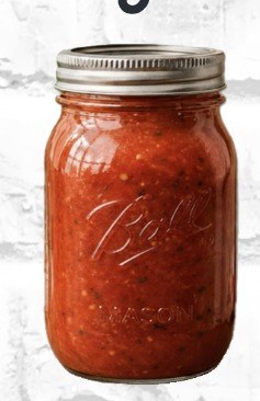 A glass mason jar filled with chunky red marinara sauce.